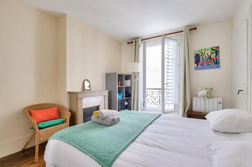 une chambre avec un lit, une chaise et une fenêtre dans l'établissement Cosy 2 BR Flat near Place d'Italie, à Paris