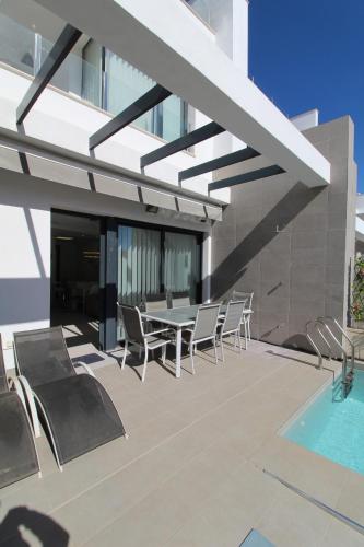 een patio met stoelen, een tafel en een zwembad bij Fabulous Villa with private pool & large roof solarium in Villamartin