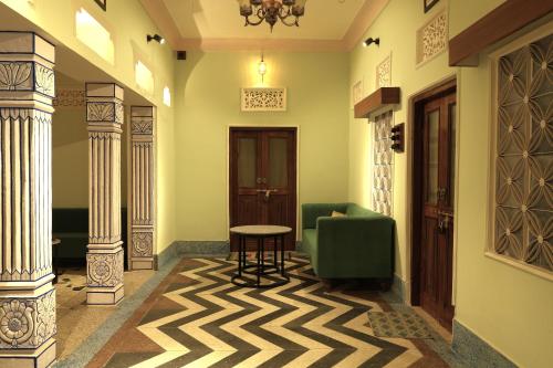 a hallway with a green chair and a table and columns at House of Amer in Jaipur
