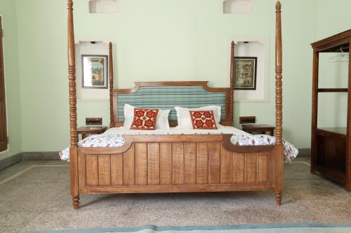 a bedroom with a large wooden bed with red pillows at House of Amer in Jaipur
