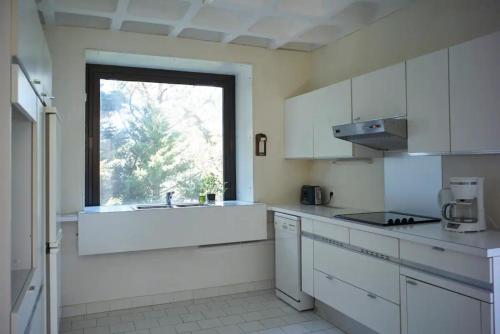 une cuisine blanche avec un évier et une fenêtre dans l'établissement Appartement accès direct à la mer, à Bormes-les-Mimosas