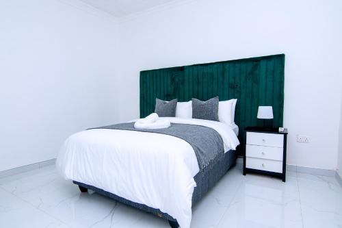 a bedroom with a large bed with a green headboard at Morning Mist Lodge in Livingstone