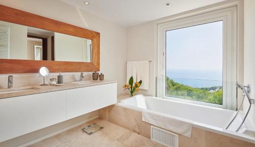 a bathroom with a tub and a large window at Can Pascalou in Canyamel
