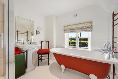une salle de bain avec une grande baignoire et un lavabo dans l'établissement Wheelwrights Cottage, à Tarporley