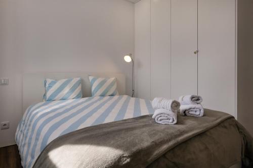a bedroom with a bed with towels on it at Cozy Figueira Apartment in Figueira da Foz