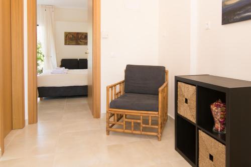 a living room with a chair and a bedroom at Angelbay Bungalows in Agia Triada