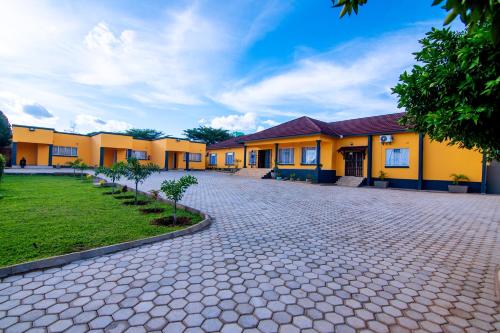 a row of yellow buildings with a driveway at Morning Mist Lodge in Livingstone