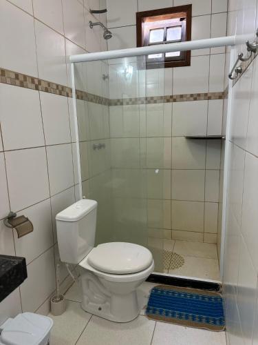 a bathroom with a toilet and a glass shower door at Suites do Peró in Cabo Frio