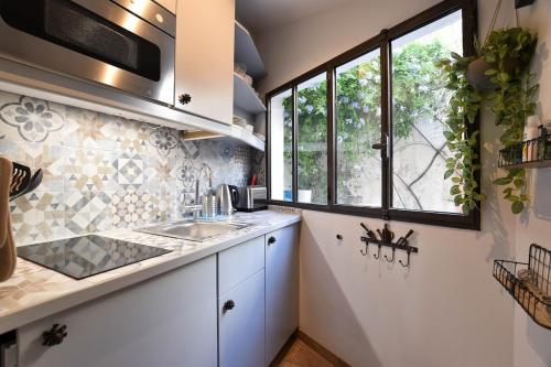 une cuisine avec un évier et une fenêtre dans l'établissement La Suite Lume - Clim et terrasse, à Arles