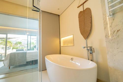 a bathroom with a white tub and a bedroom at île de Pipa - Ma Plage Hotel in Pipa
