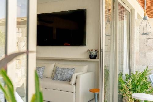 a living room with a couch and a tv on the wall at île de Pipa - Ma Plage Hotel in Pipa
