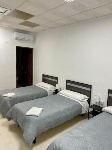 a room with three beds with towels on them at Hostal Kaizen in La Nucía