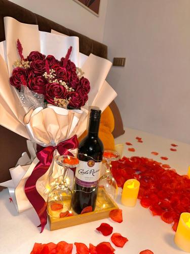 a bottle of wine and a bouquet of red roses at Vibin Chill Staycation in Manila