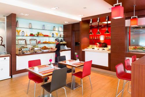 a restaurant with red chairs and a chef preparing food at ibis Vientiane Nam Phu in Vientiane