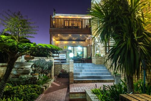 a house with stairs and palm trees in front of it at Villa Majestic for Exclusive Accommodation in Port Alfred
