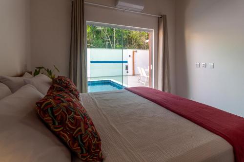 ein Schlafzimmer mit einem Bett mit Blick auf einen Pool in der Unterkunft Residencial Falésias de Pitinga in Arraial d'Ajuda