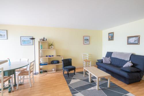 un salon avec un canapé bleu et une table dans l'établissement Le Cap Normand - Vue mer, à Cabourg