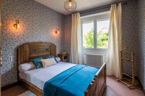 a bedroom with a bed with blue sheets and a window at La maison d autrefois in Aguessac