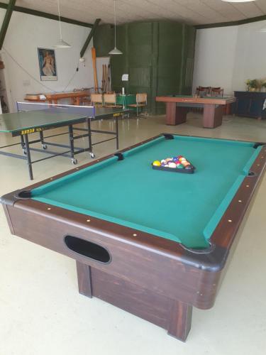 a pool table in a room with two tables at Feriestedet Skovly in Klemensker