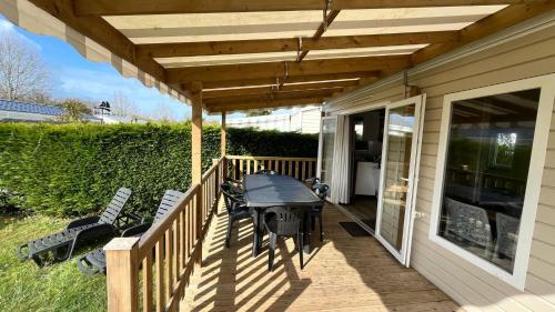 une terrasse en bois avec une table et des chaises dessus dans l'établissement Mobilhome Ile d'Oléron - 6 places - Camping 5 étoiles, à Saint-Georges-dʼOléron