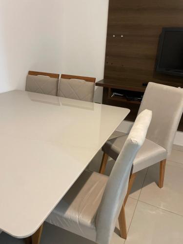 a white table with two white chairs and a television at Casa em Barueri in Barueri