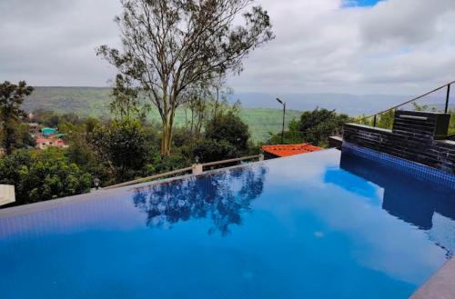 a large blue swimming pool with a view at Tulsi Villa in Panchgani