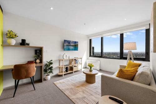 a living room with a couch and large windows at City Stays - Plus in Melbourne