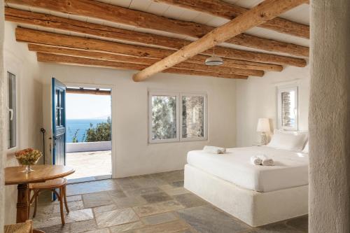 a bedroom with a bed and a view of the ocean at Amoni Andros in Agia Eleousa