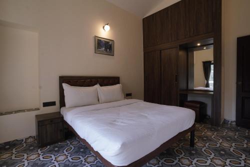 a bedroom with a white bed with a wooden cabinet at Hotel Lotus in Candolim