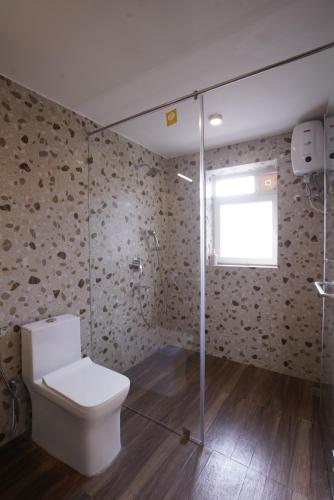 a bathroom with a toilet and a glass shower at Hotel Lotus in Candolim