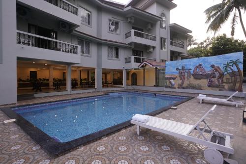 a swimming pool in front of a building at Hotel Lotus in Candolim