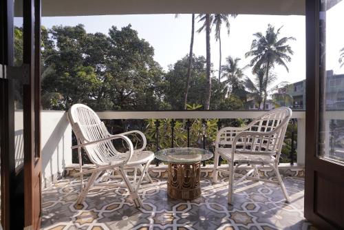 three chairs and a table on a balcony at Hotel Lotus in Candolim