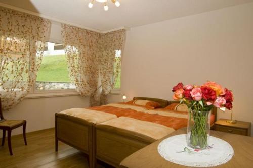 ein Schlafzimmer mit einem Bett und einer Vase aus Blumen auf einem Tisch in der Unterkunft Residenz Ambassador B01 in Leukerbad