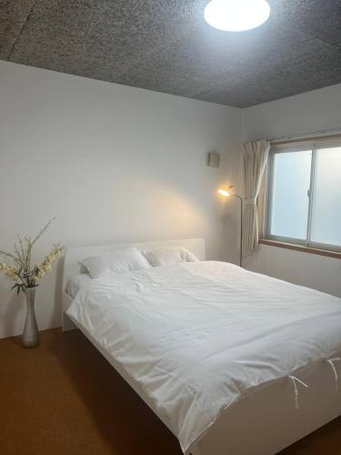 a white bed in a bedroom with a window at Sunshine in Tokyo
