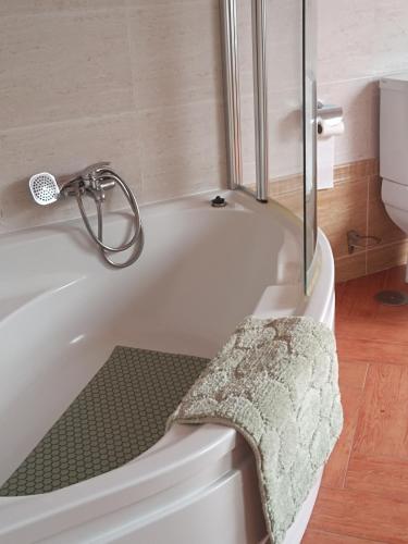 eine weiße Badewanne mit einem grünen Handtuch darauf in der Unterkunft Tralla in Corcubión