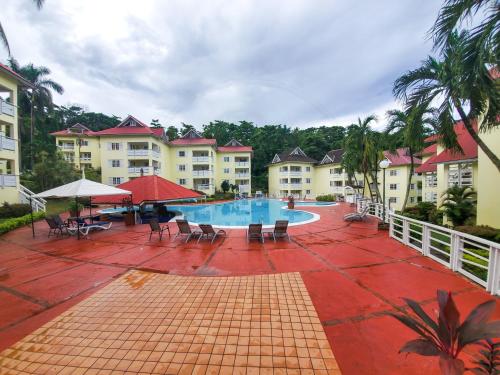 Un complejo con piscina, mesas y sillas. en Cozy Apartment at Mystic Ridge Ocho Rios, en Ocho Ríos