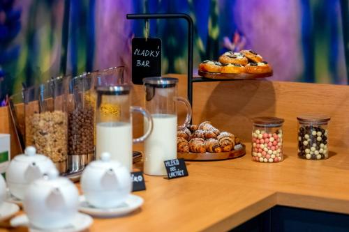 a counter with milk and different types of food at Hotel NOBILIS - Mladá Boleslav in Bradlec