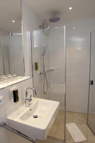 a white bathroom with a sink and a shower at Hotel ADRIA München in Munich