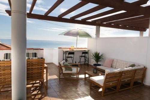 a patio with a couch and a table with an umbrella at Beachfront Apartment with Rooftop Terrace - Manilva - La Duquesa in Manilva