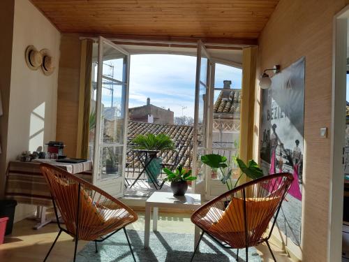 une chambre avec des chaises, une table et une fenêtre dans l'établissement Maison dans village du sud, à Villeneuve-lès-Béziers