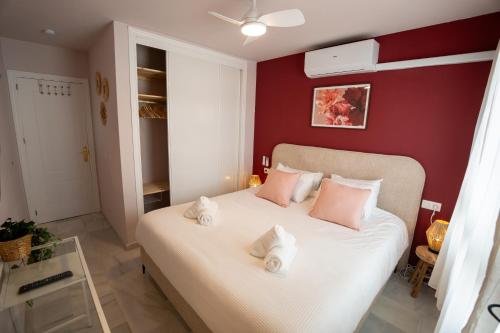 une chambre avec un lit blanc avec des oreillers roses dans l'établissement Beachfront Apartment with Rooftop Terrace - Manilva - La Duquesa, à Manilva