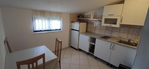 a kitchen with white cabinets and a table with a tableablish at Apartments Vlado in Rogač