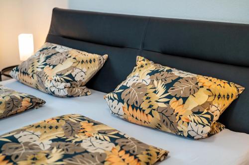 a bed with four pillows on it with a headboard at Ferienwohnung im Grünen in Oppenau