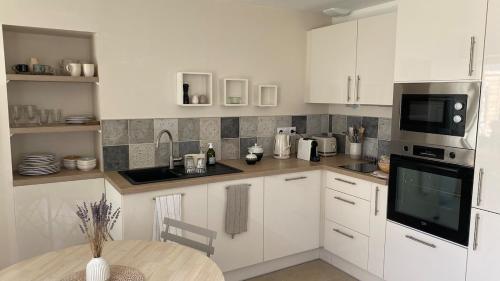 une cuisine avec des armoires blanches et une table à l'intérieur dans l'établissement Maison de charme en bord de mer, à Batz-sur-Mer