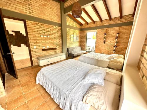a bedroom with two beds and a brick wall at Casa Boutique Calima in Restrepo