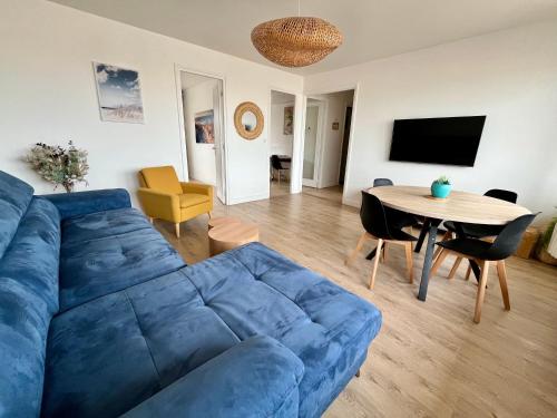 un salon avec un canapé bleu et une table dans l'établissement Appartement VUE MER, à Dunkerque