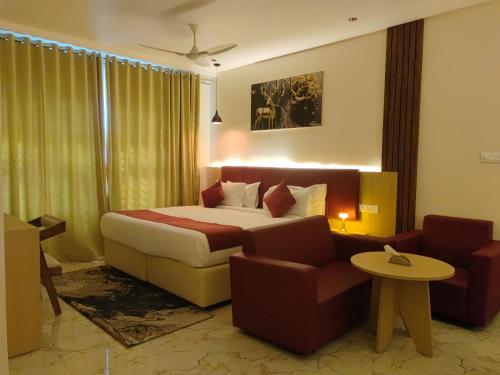 a hotel room with a bed and a couch and chairs at Hotel Meridian Blue in Warangal
