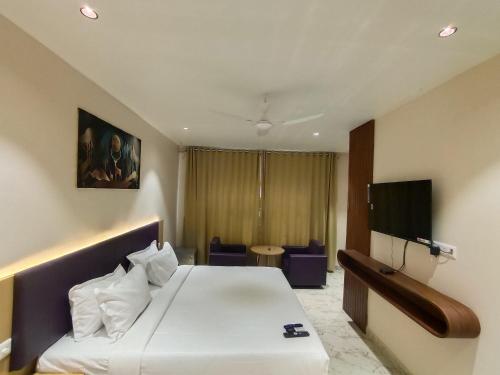 a hotel room with a bed and a flat screen tv at Hotel Meridian Blue in Warangal