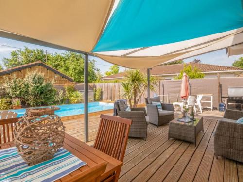 une terrasse avec une table, des chaises et un parasol dans l'établissement Kerkokos Maison familiale avec piscine, à Gujan-Mestras