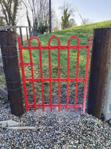 a red metal gate in front of a field at St Kevins Cottage in Hollywood